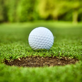 Golf ball on the green. golf ball on lip of cup